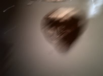 Image floue d'un objet sombre en forme de cœur sur un fond gris.